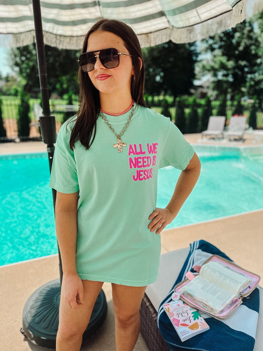 woman wearing all we need is Jesus comfort colors christian t-shirt in island reef by the pool