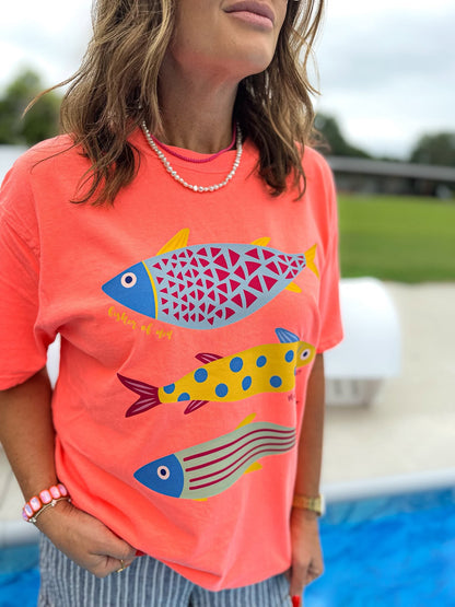 woman wearing a neon red orange fisher of men christian t-shirt with colorful fish design