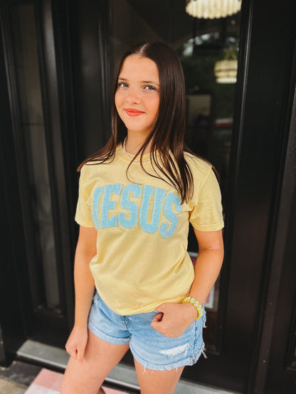 woman wearing butter comfort colors Jesus christian t-shirt with blue chenille patch